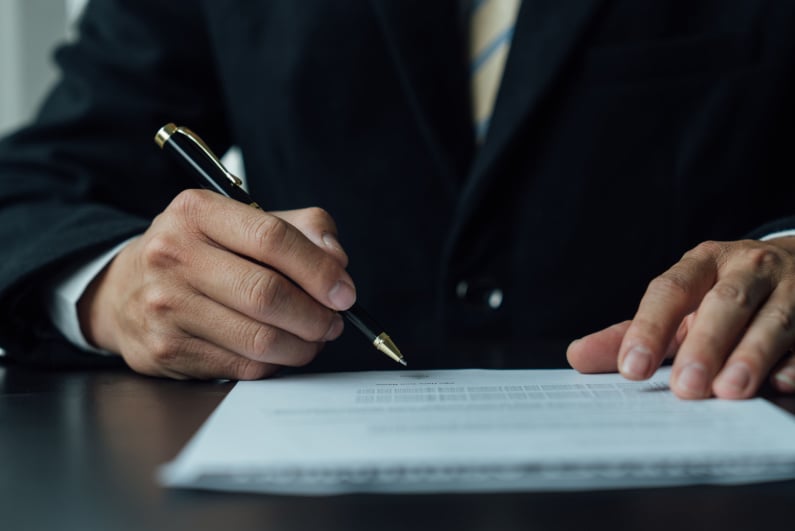 suited man signing a document